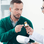 A man presents a pill to his doctor during a consultation in a medical office