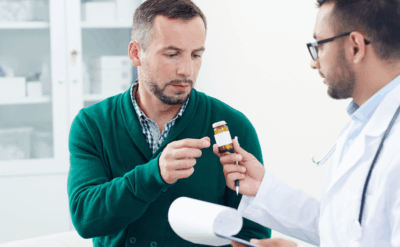 A man presents a pill to his doctor during a consultation in a medical office